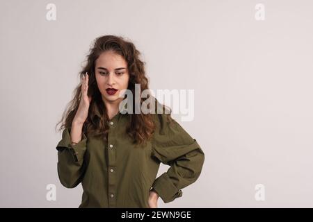 La jeune femme lève sa main sur son visage et prouve quelque chose avec une expression sérieuse Banque D'Images