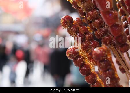 Gros plan sur la gourmande traditionnelle chinoise à sucre glace. Bâton de haws enrobés de sucre. En-cas chinois Banque D'Images