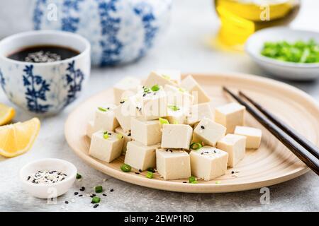 Cubes de tofu sur plaque de bambou avec baguettes et sauce soja. Supplément de viande végétalienne Banque D'Images