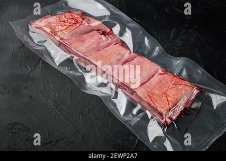 Ensemble de côtes courtes de bœuf à la viande emballées à l'aspirateur, sur fond de pierre noire Banque D'Images