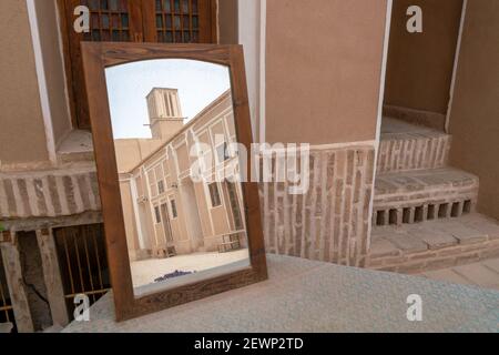 Tour éolienne, dispositif de refroidissement médiéval, se reflète dans un miroir debout sur une table dans les rues de Yazd, Iran. Banque D'Images