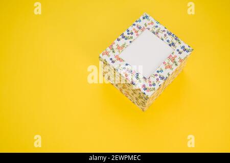 Vue en grand angle d'une boîte en carton avec fleur motifs sur fond jaune avec un espace de copie Banque D'Images