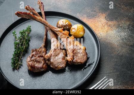 Côtelettes d'agneau cuisinées maison avec ail et carottes, sur plaque, sur fond rustique foncé ancien, avec copyspace et espace pour le texte Banque D'Images