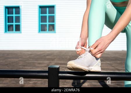 Femme portant des vêtements de sport qui noue ses baskets, se préparant à faire de l'exercice ou courir à l'extérieur. Banque D'Images