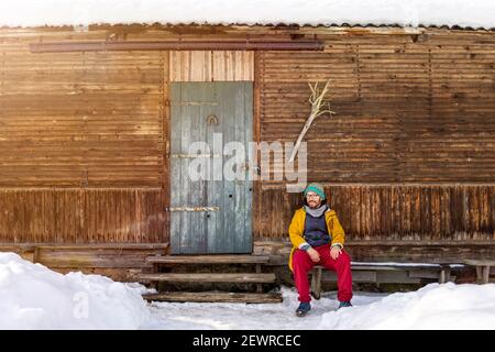 Homme assis devant un cottage traditionnel en bois, Pologne Banque D'Images