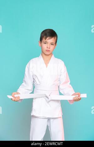 Karaté jeune garçon en uniforme blanc sur fond bleu. Concept de sport pour enfants Banque D'Images