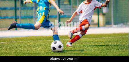 Deux footballeurs Kicking ball en équipes opposées. Duel de football ; moment de Kicking ball. Jeunes joueurs de football qui jouent à Duel et à Soccer Tourname Banque D'Images