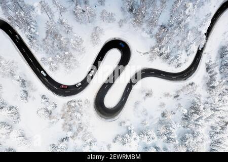 Vue aérienne de la route de montagne en forme de S le long de la forêt d'hiver couverte de neige, Suisse, Europe Banque D'Images