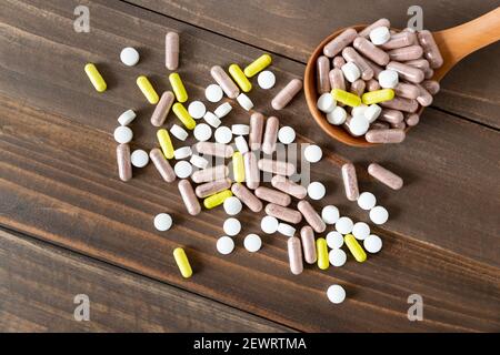 Vue de dessus d'un assortiment de pilules, comprimés et capsules pharmaceutiques sur fond de bois sombre. Banque D'Images