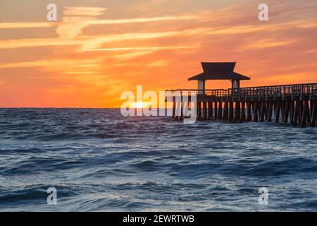 Vue sur le golfe du Mexique depuis la plage à côté de l'embarcadère de Naples, coucher de soleil, ciel doré au-dessus de l'horizon, Naples, Floride, États-Unis d'Amérique Banque D'Images