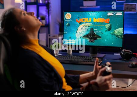 Tournoi en ligne de jeu de tir spatial gagnant utilisant un contrôleur professionnel et un ordinateur puissant. Pro Player streaming en ligne jeux vidéo nouveaux graphiques dans le studio de jeu à domicile Banque D'Images