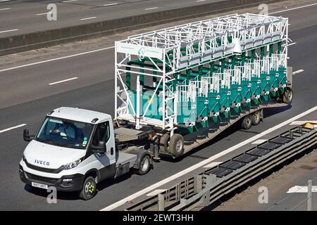 Vue aérienne du petit camion Iveco et du chargeur bas articulé remorque avec charge inhabituelle de démarrage de course de chevaux à roues portables portes sur l'autoroute du royaume-uni Banque D'Images