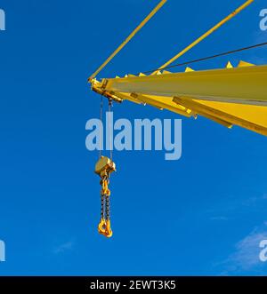 Bras de flèche de flèche de flèche de grue industrielle étendu de grande taille contre un bleu fond de ciel avec un palan à blocs Banque D'Images