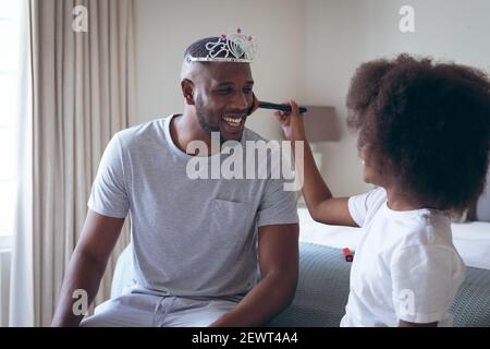 Afro-américain homme portant le tiara ayant le maquillage mis par sa fille Banque D'Images