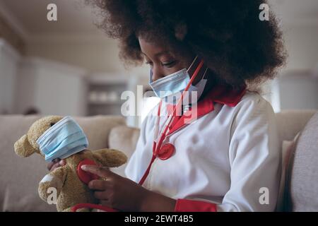 Fille afro-américaine jouant docteur et patiente avec son teddy porter Banque D'Images