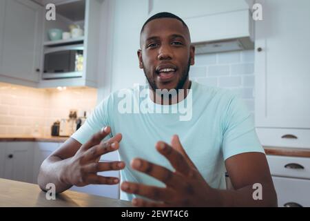 africain américain homme assis dans la cuisine ayant un chat vidéo Banque D'Images