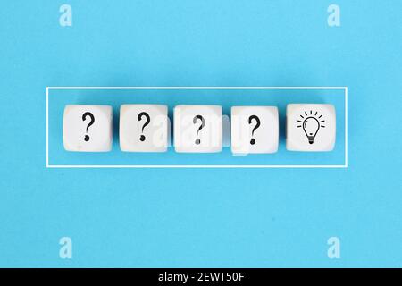 Processus de résolution de problèmes ou de formation d'idées. Point d'interrogation et icônes d'ampoule sur des cubes en bois sur fond bleu. Banque D'Images