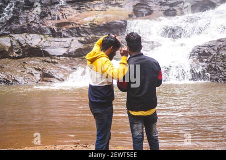 Kookal, Inde - 21 février 2021: L'homme asiatique se tient près des chutes d'eau. Images éditoriales. Banque D'Images