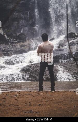 Kookal, Inde - 21 février 2021: L'homme asiatique se tient près des chutes d'eau. Images éditoriales. Banque D'Images