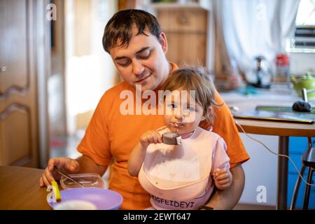 un adorable tout-petit aime manger de la glace à la popsicle sur les genoux de ses parents Banque D'Images