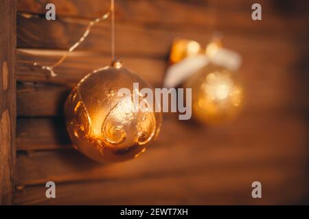 Image de deux boules en or du nouvel an suspendues sur du bois porte brun grungy mur décoré confortable maison décoration festive Banque D'Images