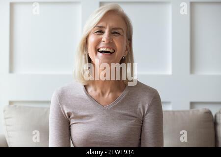 Vive portrait femme âgée s'asseoir sur le divan à regarder camera Banque D'Images