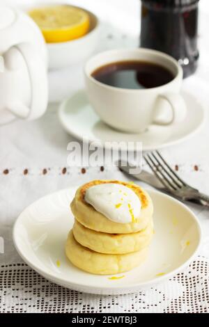 Crêpes au fromage cottage à la crème sure et au zeste de citron, servies avec du thé. Banque D'Images