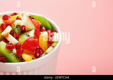 Bol avec salade de fruits sur fond rose. Tranches de fruits mûres et juteuses. Vue de dessus Banque D'Images