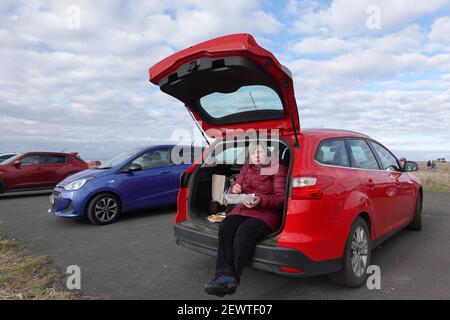 Femme, assise sur le coffre de la voiture, mangeant du poisson et des frites à Longniddry Bents Banque D'Images