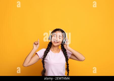 Jeune femme indienne souriante écoutant de la musique dans le casque Banque D'Images