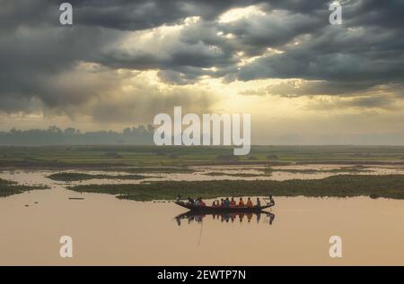 Les gens prennent le ferry sur une rivière avec vue sur le paysage rural au coucher du soleil dans un village du Bengale occidental, Inde Banque D'Images