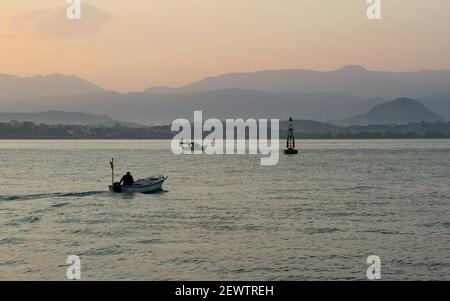 Petit bateau avec une personne seule aller pêcher depuis la marina de Santander Cantabria Espagne tôt le matin avec une vue sur la baie Banque D'Images