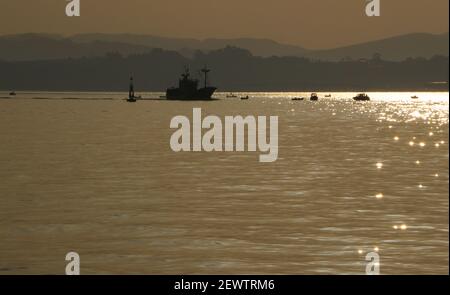 Chalutier revenant au port après une nuit de pêche silhouettée avec la lumière du soleil réfléchie Santander Cantabria Espagne hiver Banque D'Images