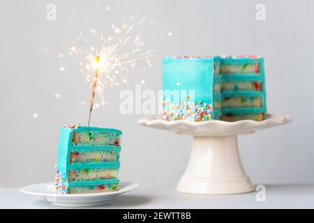Tranche de gâteau d'anniversaire avec glaçage turquoise et un sparkler Banque D'Images