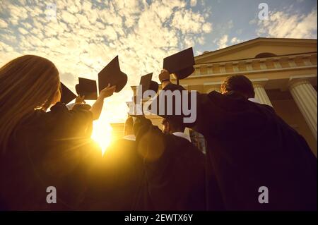 Groupe de heureux diplômés en formation et en formation les mains au coucher du soleil Banque D'Images