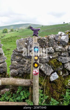 Un gant sur un marqueur de route en bois conflictuel avec une flèche jaune indiquant la voie publique et un panneau ne montrant pas de marcheurs ou d'accès, Derbyshire, Angleterre, Royaume-Uni Banque D'Images