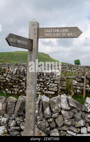 Un panneau en bois disant 'Alstonefield' et 'Gratton Lane (ce côté du mur)', Derbyshire, Angleterre, Royaume-Uni Banque D'Images