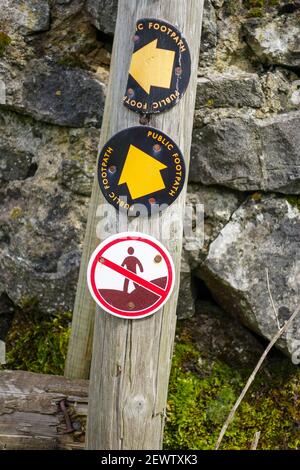 Un marqueur de route en bois conflictuel avec une flèche jaune indiquant un sentier public et un panneau ne montrant aucun marcheur ou accès, Derbyshire, Angleterre, Royaume-Uni Banque D'Images