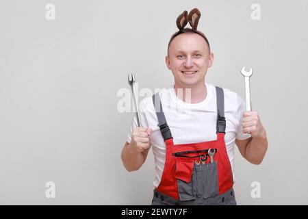 Vacances de Pâques, concept de célébration. Drôle de sourire travailleur ou mécanicien d'ingénieur porte des oreilles de lapin sur la tête et tient des clés sur fond blanc. c Banque D'Images