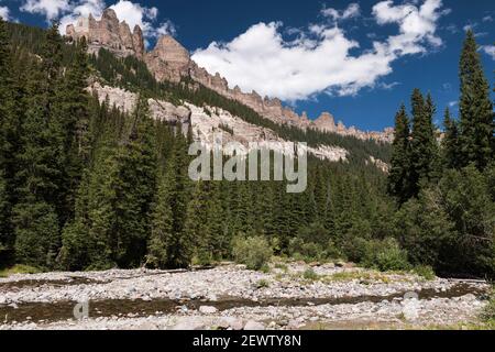 Les conditions de l'eau du milieu de l'été réduisent la fourche ouest de la rivière Cimarron en un petit ruisseau. La spectaculaire cimarron Ridge s'élève au-dessus de la vallée. Banque D'Images