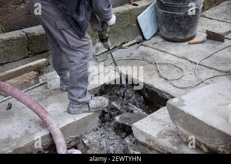 Ouvrier de construction avec marteau à inertie travaillant sur la vieille rue pavée en pierre du centre-ville historique de Saint-Jacques-de-Compostelle, Espagne Banque D'Images