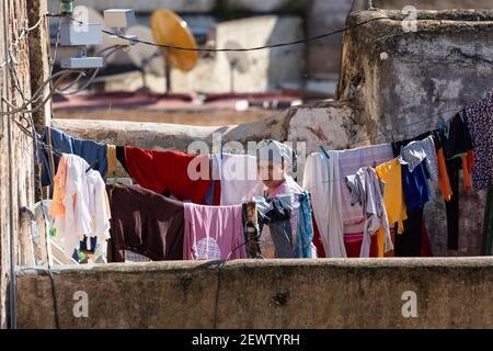 Portrait d'une femme locale qui pendait des vêtements sur une ligne de lavage sur un toit-terrasse dans la Fès médina, au Maroc Banque D'Images