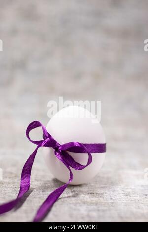 œuf de poulet emballé dans un nœud papillon violet. nourriture saine et crue. œuf de pâques, présent. Banque D'Images
