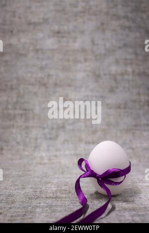 œuf de poulet emballé dans un nœud papillon violet. nourriture saine et crue. œuf de pâques, présent. Banque D'Images