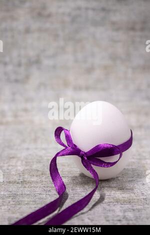 œuf de poulet emballé dans un nœud papillon violet. nourriture saine et crue. œuf de pâques, présent. Banque D'Images