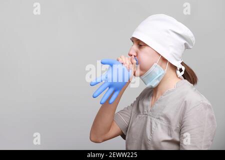 drôles souriantes infirmière ou médecin en uniforme médical et masque de protection gonfle bleu gant de latex isolé sur fond blanc. Banque D'Images