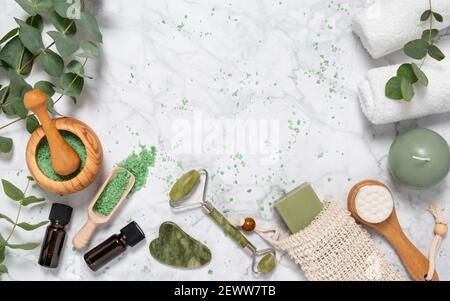Soin naturel de la peau et aromathérapie avec des bouteilles d'huile essentielle d'eucalyptus, sel de bain, rouleau de jade de beauté, gua sha sur le marbre. Spa, bien-être, massages et Banque D'Images