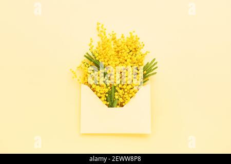 Mimosa fleur dans une enveloppe sur fond jaune. Printemps, Fête des mères ou Journée des femmes. Vue de dessus, espace de copie Banque D'Images