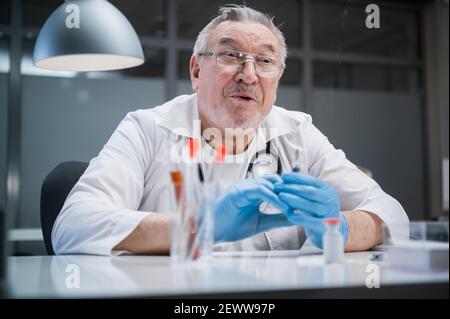 Le médecin est surpris. Avant de donner l'injection, le médecin libère l'air et une partie du médicament de la seringue dans son bureau au Banque D'Images