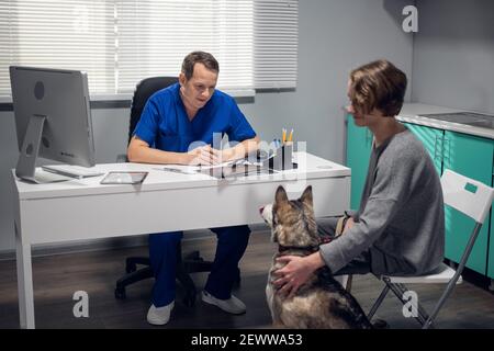 Une jeune femme avec un chien husky ayant un rendez-vous dans une clinique vétérinaire Banque D'Images